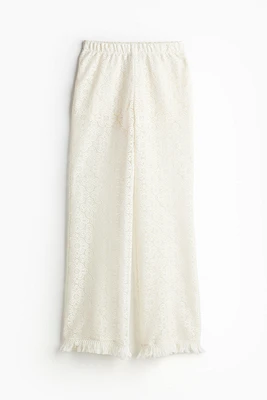 Pantalon évasé en dentelle avec bords frangés
