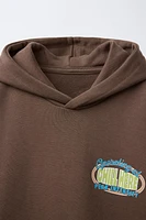 SWEAT À CAPUCHE ET INSCRIPTION